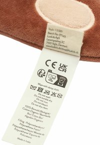 Brown plush textile with tan accents, featuring a care label detailing cleaning instructions. Material: organic cotton, polyurethane foam filling.