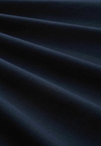 Donker marineblauwe stof met een gestructureerd oppervlak, gekenmerkt door zachte plooien en een gladde afwerking, die het licht subtiel weerkaatst over de plooien.
