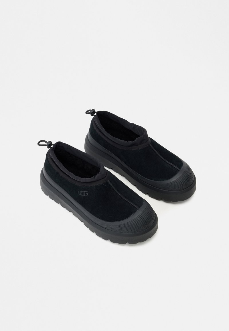 Μαύρα παπούτσια slip-on από σουέτ με αφρώδη γιακά, υφασμάτινη αντιολισθητική σόλα και ρυθμιζόμενες λεπτομέρειες με κορδόνια.