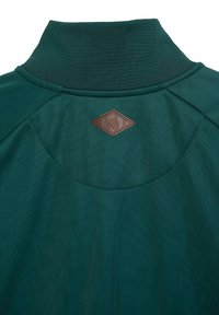 Green pullover with a high collar, featuring a textured fabric and a brown leather patch in a diamond shape at the back.
