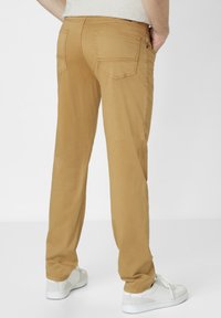 Khaki pants with a straight-leg design, five pockets, and a smooth texture. Worn with white sneakers, visible stitching along the seams.