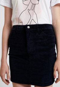 Mörkblå kordkjol med en figursydd passform, har framfickor, en central söm och en silverknappstängning i midjan.