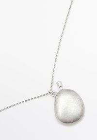 Collana d'argento con un grande pendente arrotondato con superficie testurizzata e un piccolo anello per l'attacco, su una catena delicata.