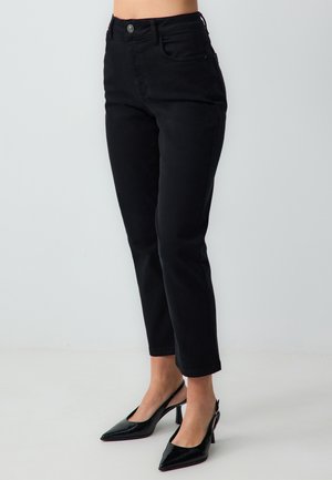 Jeans noirs ajustés, en denim. Présentent un bouton à l'avant, des poches et une finition crop. Associés à des talons en cuir laqué noirs.