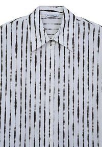 Camicia bianca con colletto a punta, caratterizzata da un motivo a righe verticali nere e bottoni sul davanti, realizzata in tessuto liscio.