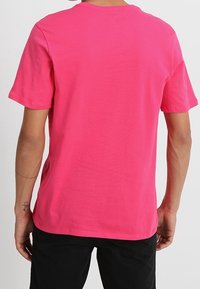 Kortärmad t-shirt med rund halsringning i stark rosa bomull. Har en jämn textur, enkel design och en avslappnad passform utan synlig logga.