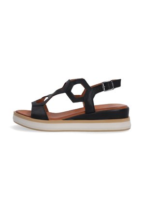 Sort lædersandal med hexagonale udskæringer, justerbar ankelrem og en to-farvet platformssål i beige og sort.