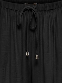 Tissu noir avec taille élastique froncée et cordon noué avec embouts métalliques argentés aux extrémités.