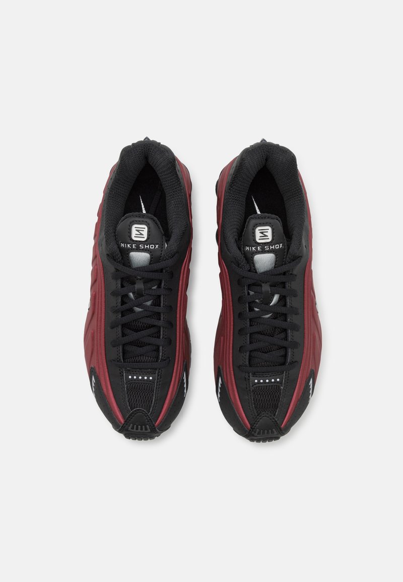 Baskets Nike Shox en noir et maroon. Dotées d'une tige texturée, d'un col rembourré et de lacets plats. Logo notable sur la languette et au talon.