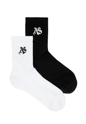 Pari ribbineuloksisia sukkia, yksi musta ja yksi valkoinen, kummassakin tyylitelty "AS" -kirjainpistely lähellä yläosaa.