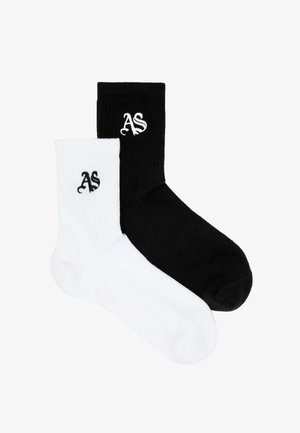 Paire de chaussettes côtelées, une noire et une blanche, chacune avec les lettres stylisées "AS" brodées près du haut.
