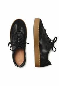 Zapatos de cuero negro y ante con punta redonda, cordones en la parte delantera y suela de goma marrón. Parte superior lisa con acentos texturizados en los laterales.