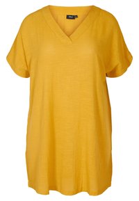 Senapsgul tunika med V-ringning och korta, uppvikta ärmar. Tillverkad av lätt tyg med en något texturerad yta.