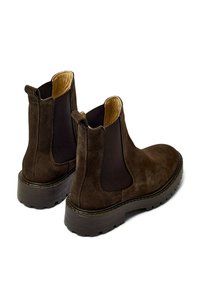 Botas Chelsea de ante marrón con paneles laterales elásticos, lengüetas para facilitar el calzado y suelas gruesas de goma para tracción y durabilidad.