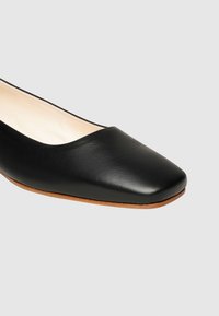 Schwarze Leder-Ballerinas mit eckiger Zehenform, glatter Textur und einer hellbraunen, leicht flexiblen Sohle für Komfort und Stabilität.