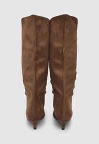 Bottes en suède marron à hauteur de genou avec une forme ajustée, un bout pointu et un talon de 5 cm. Présente une texture lisse et un design minimaliste.
