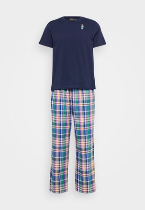 T-shirt en coton marine avec un petit logo de ours brodé et un pantalon de pyjama à carreaux disponible en plusieurs couleurs, offrant une coupe ample et une taille élastique.
