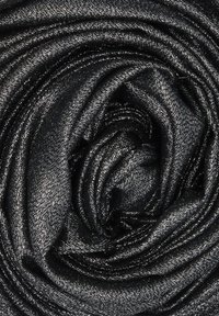 Tessuto nero con una texture liscia e lucida, disposto a spirale che ricorda una rosa. Sono visibili sottili fili metallici.