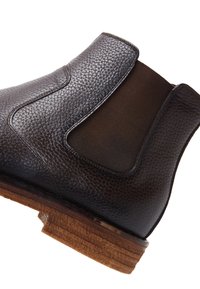 Bruine leren Chelsea-boot met elastische zijkanten, een textuur oppervlak en een contrasterende lichtbruine houten zool.