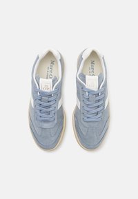 Kék velúr sneakers fehér részletekkel, kerek orral, lapos fűzővel és texturált gumitalppal; a nyelvén dombornyomott logo található.