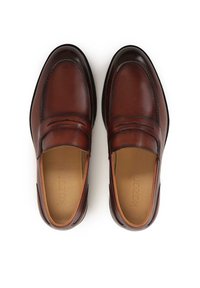 Mocassins en cuir marron avec une texture lisse, un design classique et un détail de couture subtil le long de l'empeigne. Semelle plate en caoutchouc.