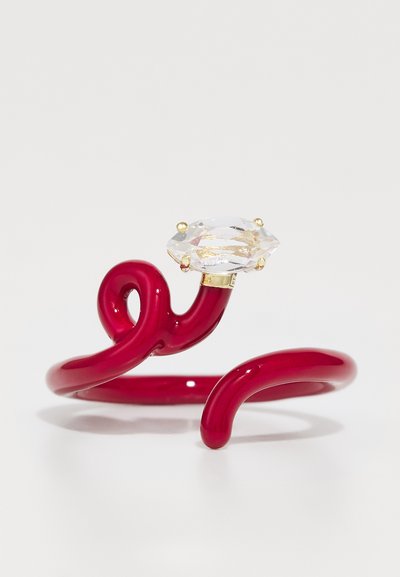 Roter, glänzender Plastikring mit einem gedrehten Design, ausgestattet mit einem großen klaren, facettierten Stein, der in goldfarbenem Zubehör montiert ist.