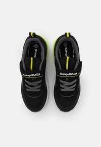 Ein Paar schwarze und graue KangaROOS Sneaker mit neongelben Akzenten, Klettverschluss und grauen Schnürsenkeln, von oben auf einem weißen Hintergrund betrachtet.