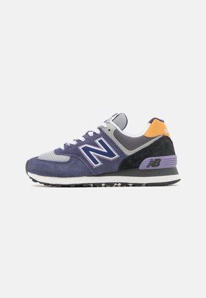 Męski sneaker New Balance w fioletowym zamszu i siateczce z szarymi, czarnymi i pomarańczowymi akcentami oraz białymi sznurowadłami, widoczny z zewnętrznej strony.