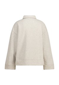 Vaalean beige neulepaita, jossa on kaulus, pitkät hihat ja lyhyt leikkaus. Valmistettu pehmeästä, teksturoidusta kankaasta, jossa on minimaaliset saumat ja ei näkyvää metalliosaa.