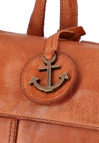 Borsa in pelle marrone con una patch circolare contenente un emblema di un'ancora in bronzo. Cuciture distintive e superficie liscia e strutturata.