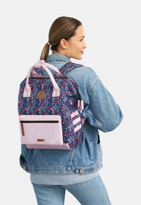 Floral-patterned backpack in dark blue and pink, featuring dual handles, adjustable straps, and a front zippered pocket with a contrasting base.