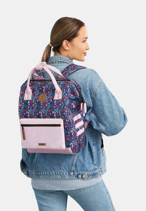 Sac à dos à motif floral en bleu foncé et rose, avec des poignées doubles, des bretelles ajustables et une poche avant zippée avec une base contrastante.