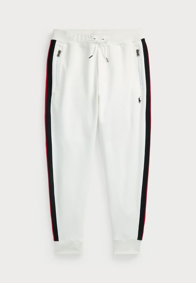 Baldos sportiniai džinsai su juodai raudonomis šoninėmis juostelėmis, elastingas juosmuo su raišteliu, užtrauktukai ant kišenių ir siuvinėtas logotipas priekyje.