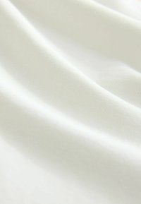 Țesătură albă cu o textură netedă, care prezintă un model fin cu nervuri, căzând moale cu pliuri delicate și un ușor luciu.