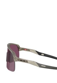 Occhiali da sole con una montatura grigia trasparente e aste grigie scure, dotati di ampie lenti viola e di un accento testurizzato vicino alle cerniere.