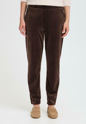 Pantalons en velours côtelé marron avec des côtes verticales, une coupe décontractée et une taille élastique ; associés à des chaussures slip-on beiges.