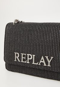 Portafoglio nero con texture, dotato di un flap pieghevole, caratterizzato da un logo "REPLAY" in argento e hardware metallico nella parte superiore.