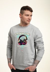 Felpa grigia con una grafica colorata di cuffie e il testo "STRAIGHT FIRE" e "TROPICAL TWIST", posizionata su uno sfondo semplice.