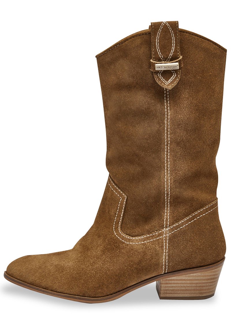 Botte western en daim marron avec un bout effilé, des coutures courbées sur les côtés et un petit talon empilé. Elle présente une sangle décorative en haut.