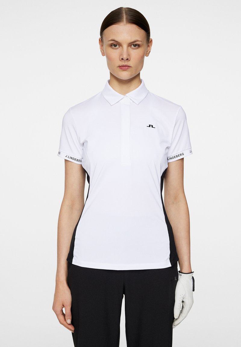 Vit pikétröja med krage, korta ärmar, svarta sidopaneler och en liten logga på bröstet. Bärs med svarta byxor och en handske.