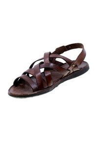 Sandali in pelle marrone con cinturini incrociati, design con punta aperta e suola piatta con una leggera curvatura. Accenti di ferramenta visibili.
