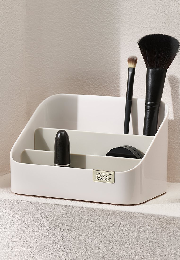 Weißer Plastik-Make-up-Organizer mit abgerundeten Kanten, der zwei Fächer für Pinsel und Kosmetikprodukte bietet und eine glatte Textur aufweist.