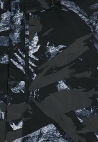 Tissu noir avec des motifs abstraits de coups de pinceau bleus et gris. Texture lisse avec une finition mate. Lignes de couture visibles près de la couture.