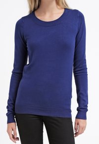 Donkerblauwe gebreide trui met lange mouwen en een ronde halslijn. Heeft een slim fit en ribgebreide randen bij de mouwen en taille.
