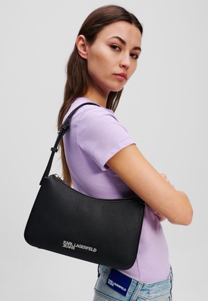 Borsa a spalla in pelle nera con design curvo, zip argentata e logo "KARL LAGERFELD JEANS" impresso sul frontale.
