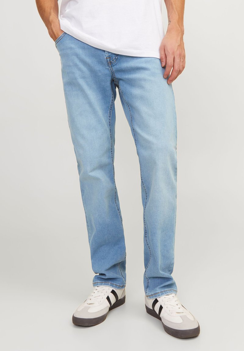 Lyseblå denimjeans med rett benkutt, fem lommers design og kontraststing. Kombinert med hvite sneakers.
