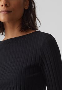 Zwart geribbelde lange mouwen top met een ronde halslijn en textiel met structuur. Beschikt over verticale strepen en een aansluitend ontwerp.