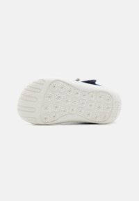Soletta delle scarpe in gomma bianca testurizzata, caratterizzata da motivi di grip circolari e il nome del marchio "CAMPER" impresso sul tallone.