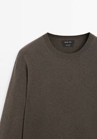 Maglione girocollo in cashmere marrone con colletto a coste e maniche lunghe, piegato su uno sfondo bianco.