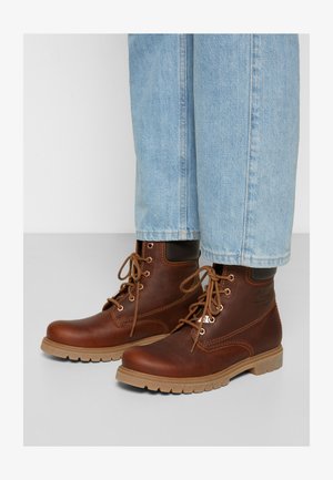 Braune Leder-Schnürstiefel mit runden Zehen, Gummisohle und hellbraunen Akzenten, kombiniert mit ausgewaschenen blauen Jeans im geraden Schnitt.